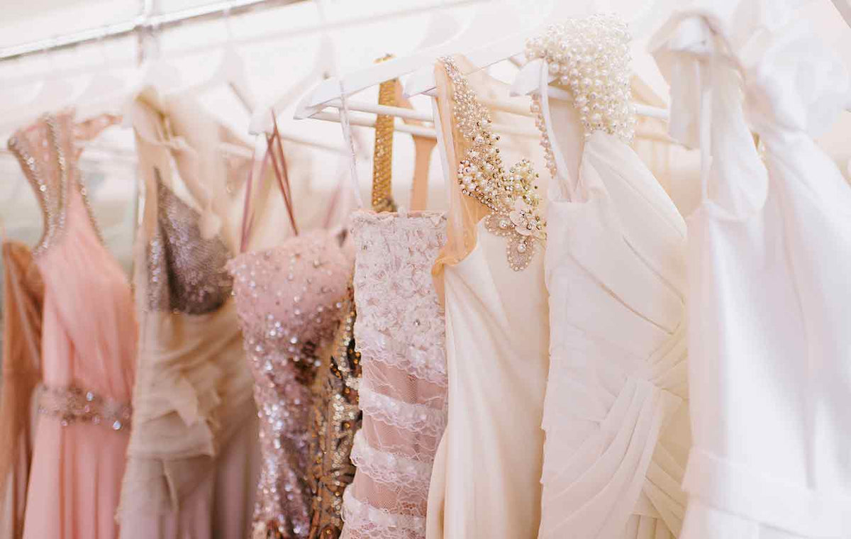 Close up of a row of hanging formal dresses with different colors and embellishments.